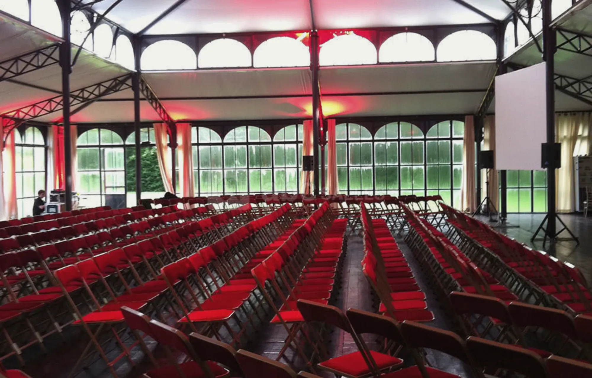 The Orangerie in plenary, rows of red chairs under the glass