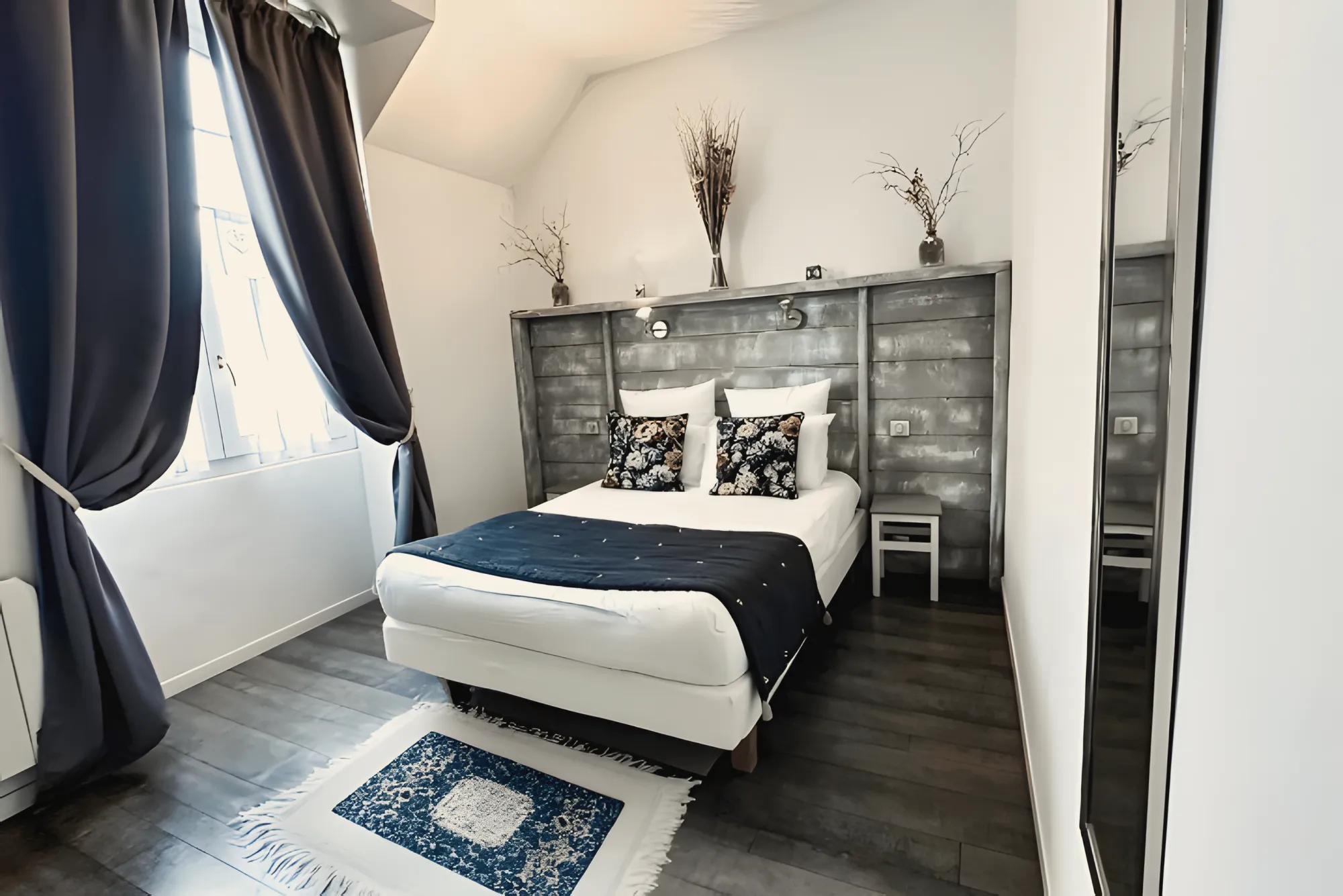 A bedroom of the gîte, navy curtains, a grey wooden headboard