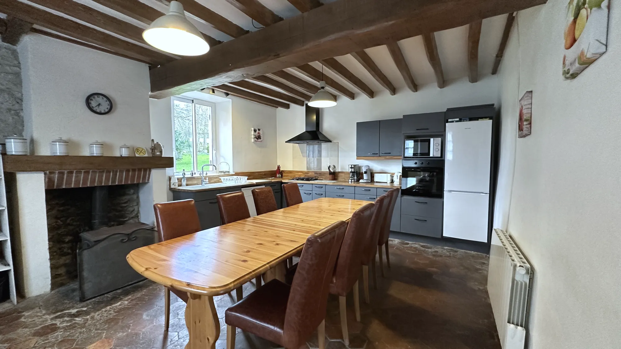 The Aile Groupe kitchen, a long pine table and a fireplace